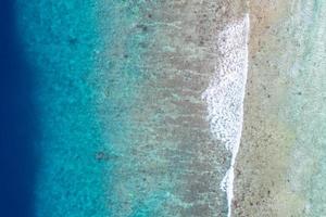vista aérea al mar, vista superior del increíble fondo del océano natural. colores de agua azul brillante, playa de la laguna con olas salpicando en el día soleado. foto de drones voladores, asombroso paisaje natural con arrecife de coral