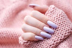 manos de niña con una manicura violeta suave. foto