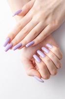 manos de una chica con una manicura violeta suave sobre un fondo blanco.