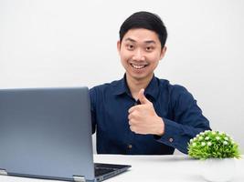 Asian man sit at workplace with laptop show thumb up smile white background photo