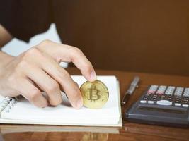 Close up hand hold bitcoin on workspace on the desk photo