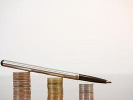 Closeup pen on coins growing up on the table white background photo