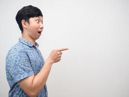 Asian man blue shirt side view excited point finger at copy space photo