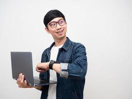 joven empresario gafas sosteniendo portátil mostrar reloj sonrisa mirando espacio de copia foto