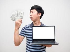 camisa a rayas de hombre emocionado con ganar dinero con el trabajo sosteniendo la pantalla blanca de la computadora portátil aislada foto