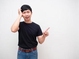 Young man black shirt confused scratch head point finger and smile photo