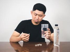 hombre enfermo asustado de comer medicina en la mesa foto