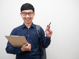 Man wearing glasses holding clipboard with backpak point pen at copy space photo