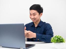 hombre trabajando en línea con una laptop en la mesa, hombre alegre usando una laptop llamando a su trabajo foto