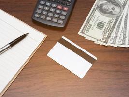 Credit card with calculator workspace and money on table top view photo