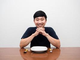 Positive man sit ready to have dinner with the gentle smile,Empty dish cutlery on the table photo