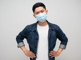 Young man jeans shirt wearing medical mask hand at waist serious emotion photo