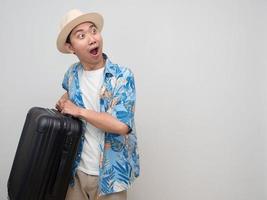 Young man wear hat beach shirt feels amazed with holiday hold luggage photo