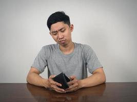 Poor man sitting feels sadness about no money hold empty wallet in hand photo