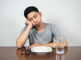 Asian man feels bored food looking at rice and water at the table photo