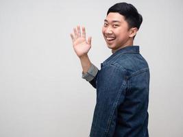 camisa de jeans de hombre asiático alegre sonriente dar la vuelta para decir hola, hombre amable decir hola foto