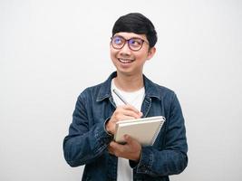 Man jeans shirt wearing  glasses writing on diary looking up photo