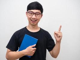 Handsome man wearing glasses gesture confident holding blue notebook get idea point finger up photo