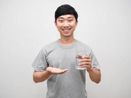 Positive young man holding medicine with glass of water gentle smile isolated photo