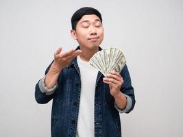 Asian man jeans shirt gesture smell his money in hand isolated photo