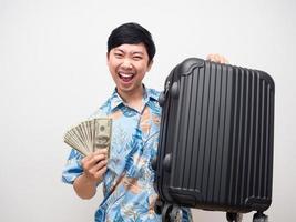 Positive man beach shirt hold a lot of money with luggage feels happy about vacation photo