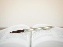 Pen on open text book white background photo