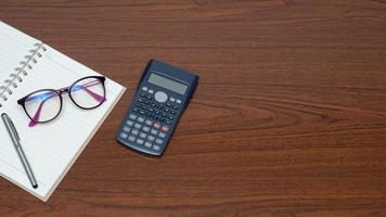 espacio de trabajo en la vista superior de la mesa de madera, calculadora de gafas portátiles en la mesa foto