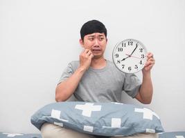 Asian man wake up late looking at analog clock feel shocked photo