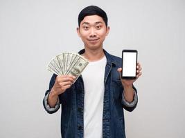 Positive man jeans shirt hold money and mobile phone isolated photo