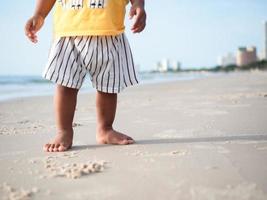 Close up feet of kid standing on the beach with beautiful ocean background photo