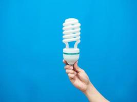 Hand holding light lamp energy save blue background isolated photo