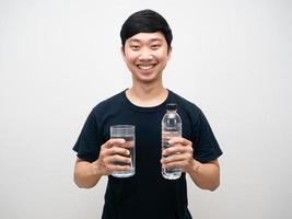retrato positivo hombre sujetando un vaso con una botella de agua feliz sonrisa fondo blanco. foto