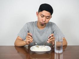 el hombre asiático se siente aburrido, la comida no quiere comer arroz en la mesa foto