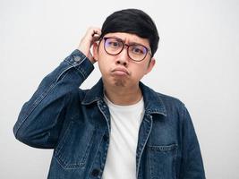 Asian man wearing glasses jeans shirt confused and scratch head studio shot photo