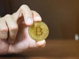 Close up man hand showing golden bitcoin on the table photo