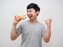 Young man happy gesture fist up about eatting sandwich in hand photo