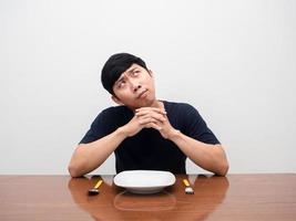 Man with cutlery and dish on table thinking about food looking up photo