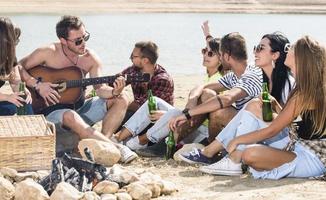 verano, vacaciones, vacaciones, música, concepto de gente feliz - grupo de amigos con guitarra divirtiéndose en la playa foto