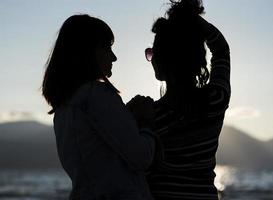 silhouettes of girlfriends at sunset hugging. photo