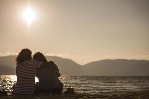 vista trasera de una feliz pareja romántica disfrutando de la hermosa puesta de sol en la playa. concepto de estilo de vida de jubilación de vacaciones de viaje foto