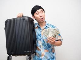 Asian man beach shirt holding luggage with money feels excited looking at copy space photo