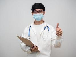 Handsome doctor wearing medical mask hold check list board thumb up portrait photo