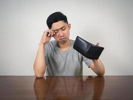 Young man crying about no money in his wallet on table photo