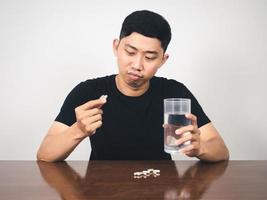 Young man feels bored hold pill and water,Man scared to eat medicine photo