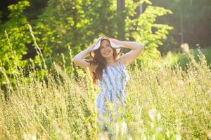 Young woman walking among wildflowers on sunny summer day. Concept of the joy of communicating with summer nature photo