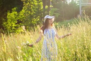 Young woman picking flowers in the meadow in summer evening photo