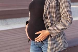 Active pregnancy concept. Close-up of belly of young business or student pregnant woman. Future mom working or studying on her late pregnancy period. photo