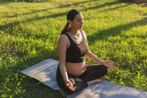 Young pregnant woman meditating in nature, practice yoga. Care of health and pregnancy photo