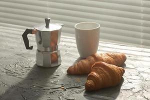 desayuno con croissant y café y cafetera moka. concepto de comida y desayuno por la mañana. foto