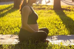 Close-up of pregnant woman meditating in nature, practice yoga. Care of health and pregnancy photo